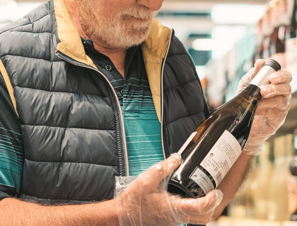 Cliente revisando una botella de vino con el control de calidad de etiquetas garantizando una información clara.